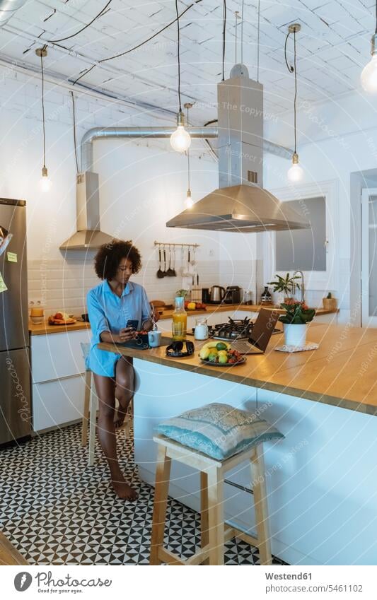 Woman having breakfast in her kitchen, using smartphone eating Breakfast Fruit Fruits Smartphone iPhone Smartphones laptop Laptop Computers laptops notebook use