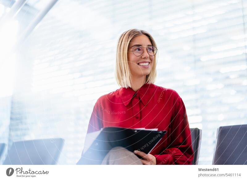 Smiling young businesswoman with folder sitting in waiting area Occupation Work job jobs profession professional occupation business life business world