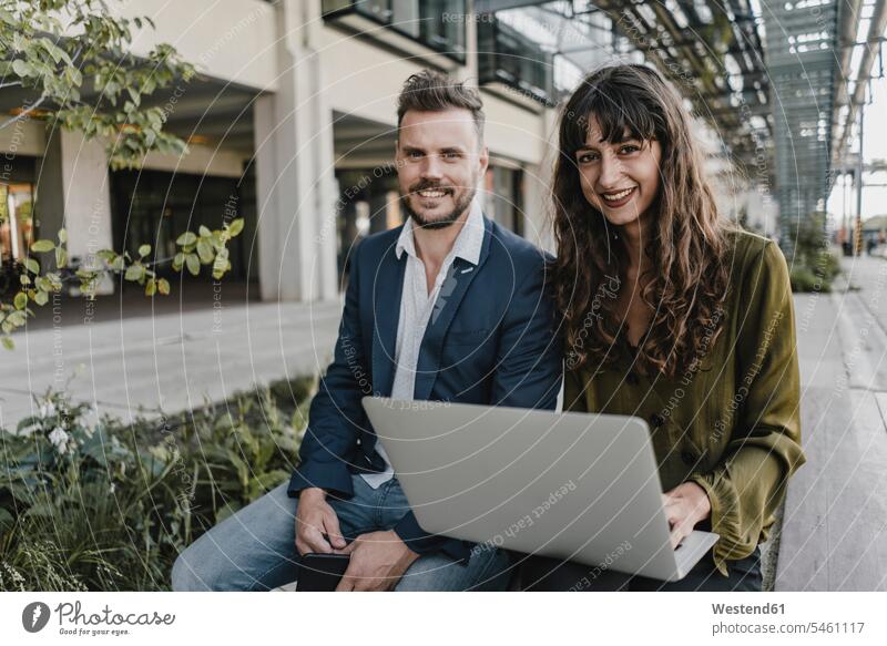 Portait of smiling businessman and casual businesswoman using laptop outdoors human human being human beings humans person persons caucasian appearance