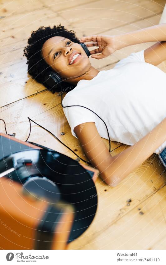 Young woman at home listening vinyl records, lying on ground Listening Music record player turntable headphones headset young women young woman analogue Media