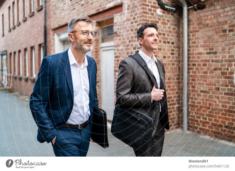 Two smiling businessmen walking at an old brick building brick buildings smile going executive Executives manager Business Meeting business conference meeting