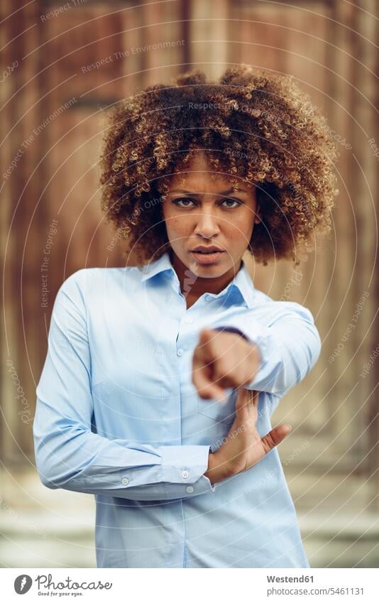 Portrait of serious woman with afro hairstyle pointing with her finger outdoors portrait portraits point at pointing at females women Afro Afros earnest