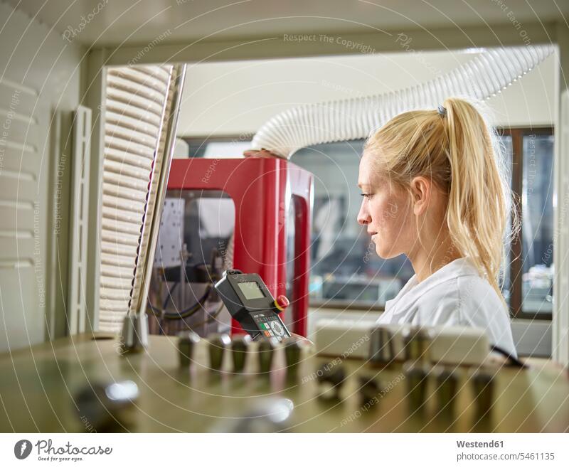 Female technician maintaining CNC machine woman females women working At Work industry industrial female technician female technicians CNC machines Adults