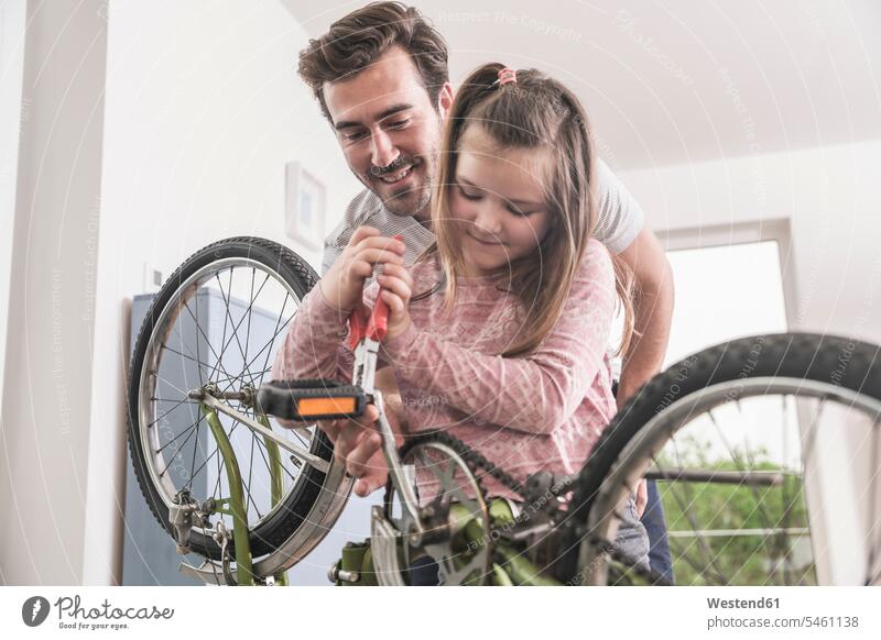 Young man and little girl repairing bicycle together Germany Single Father Showing show one parent sustainability sustainable pliers grippers DIY do-it-yourself