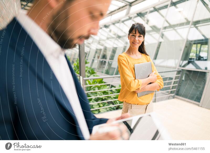 Smiling female entrepreneur looking at male colleague using digital tablet in office color image colour image indoors indoor shot indoor shots interior