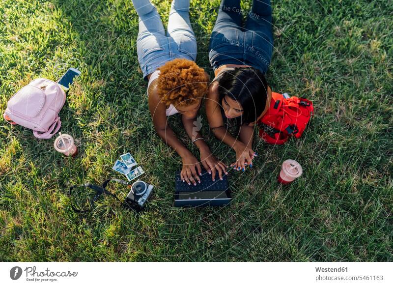 Two female friends relaxing in a park using a tablet parks digitizer Tablet Computer Tablet PC Tablet Computers iPad Digital Tablet digital tablets relaxed