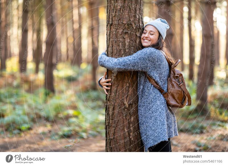 Happy female hiker embracing tree while hiking in Cannock Chase woodland during winter color image colour image outdoors location shots outdoor shot