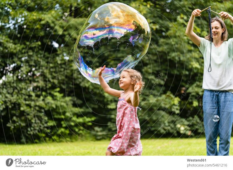 Mother and daughter playing with bubble at park color image colour image outdoors location shots outdoor shot outdoor shots day daylight shot daylight shots