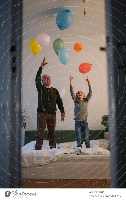 Happy grandfather and grandson playing with balloons on bed at home human human being human beings humans person persons caucasian appearance