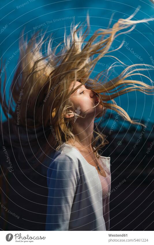Long-haired young woman shaking her hair outdoors at night blond blond hair blonde hair shake females women people persons human being humans human beings