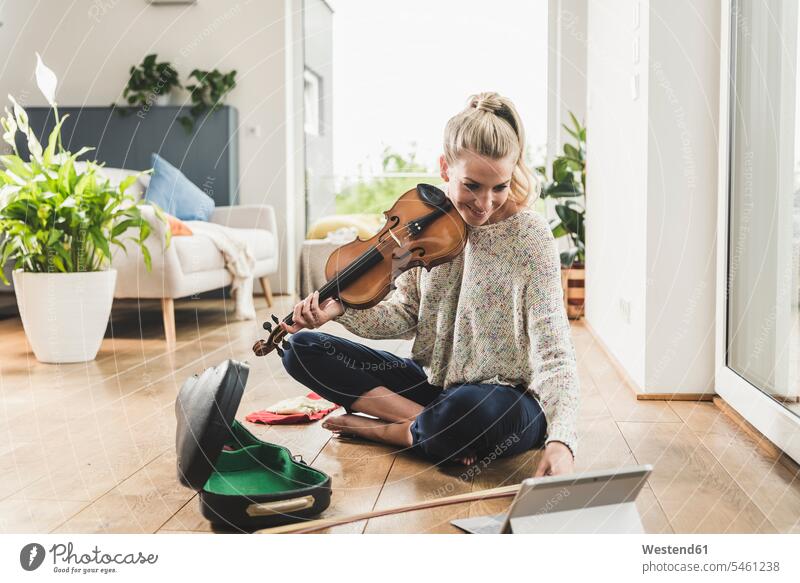 Woman with tablet sitting on the floor at home playing violin human human being human beings humans person persons celibate celibates singles solitary people