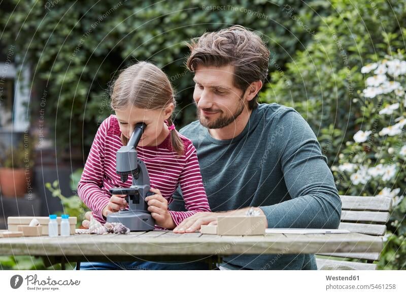 Father and daughter using microscope together at garden table daughters Garden Table Outdoor Table microscopes father pa fathers daddy dads papa child children