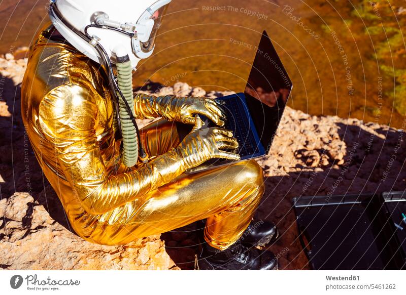 Astronaut using laptop while sitting on moon color image colour image outdoors location shots outdoor shot outdoor shots side view sideview View From Side