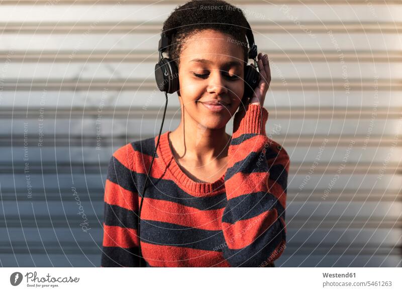 Portrait of smiling young woman listening music with headphones females women portrait portraits hearing smile Adults grown-ups grownups adult people persons