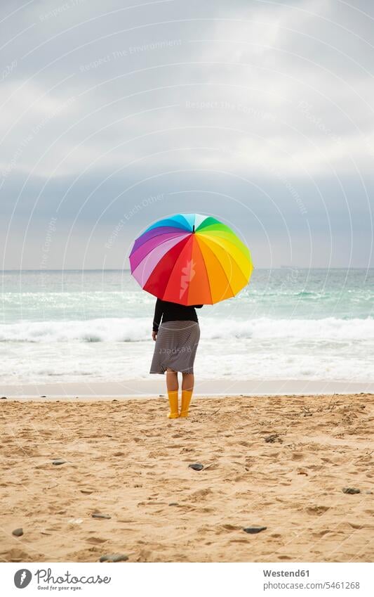 Woman with colorful umbrella sitting on the beach prismatic colours Rainbow Color prismatic colors beaches woman females women multicultural Tolerance tolerant