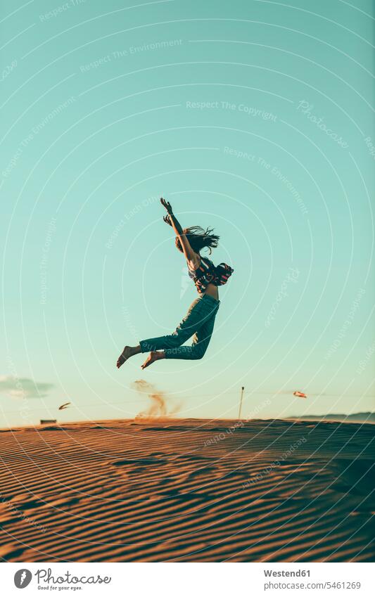Young woman jumping in desert landscape Leaping landscapes scenery terrain females women Deserts jumps Adults grown-ups grownups adult people persons