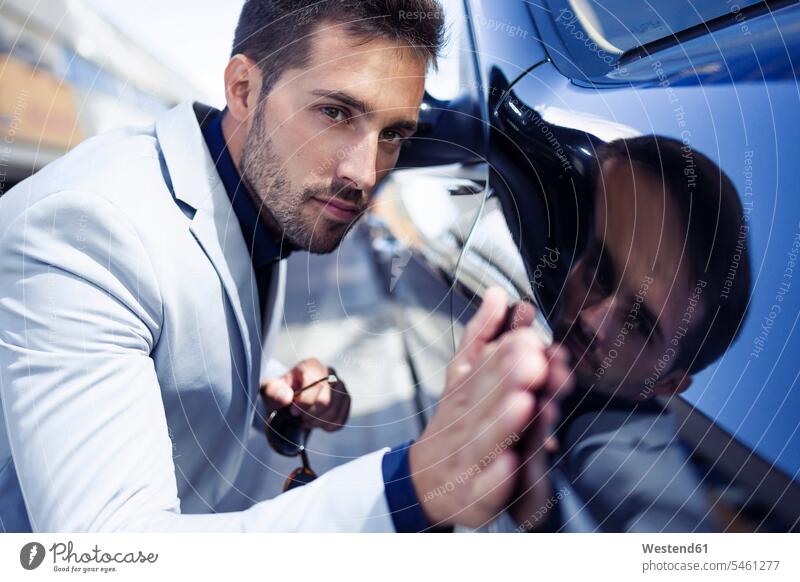 Young businessman stroking his polished car Businessman Business man Businessmen Business men automobile Auto cars motorcars Automobiles on the move on the way