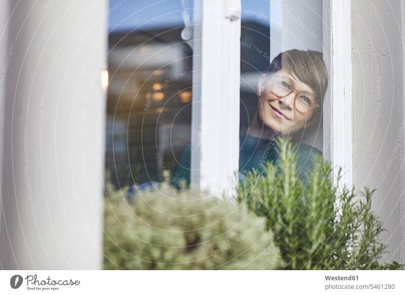 Smiling woman at home looking out of window human human being human beings humans person persons celibate celibates singles solitary people solitary person