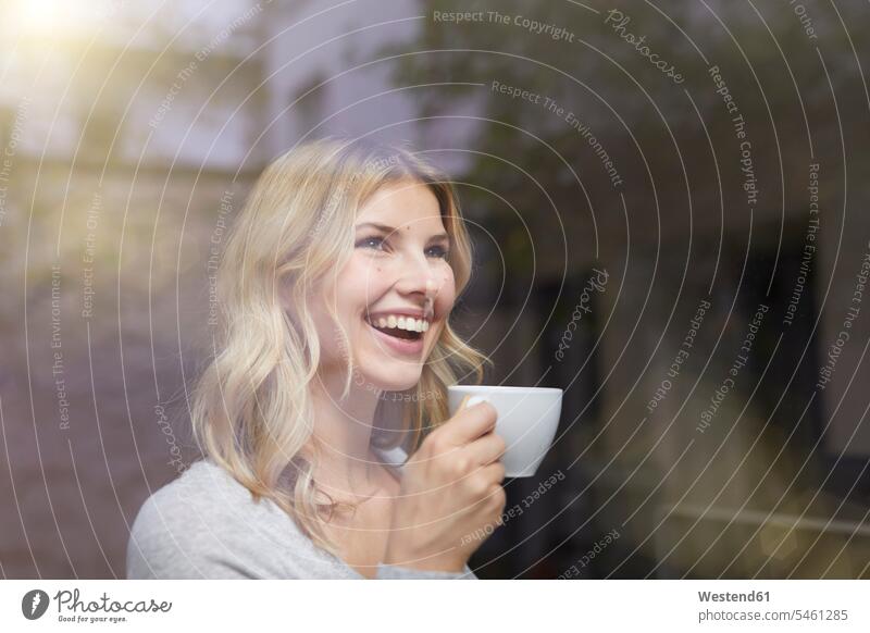 Portrait of laughing woman with cup of coffee behind windowpane Laughter Coffee Coffee Cup Coffee Cups portrait portraits females women windows window glass