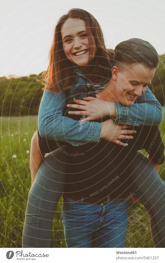 Young man giving his happy girlfriend a piggyback ride in nature natural world young Girlfriends girl friend girl friends men males happiness Adults grown-ups