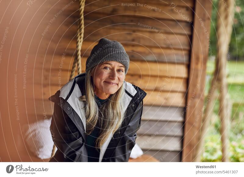 Smiling mature woman wearing knit hat in back yard color image colour image outdoors location shots outdoor shot outdoor shots day daylight shot daylight shots