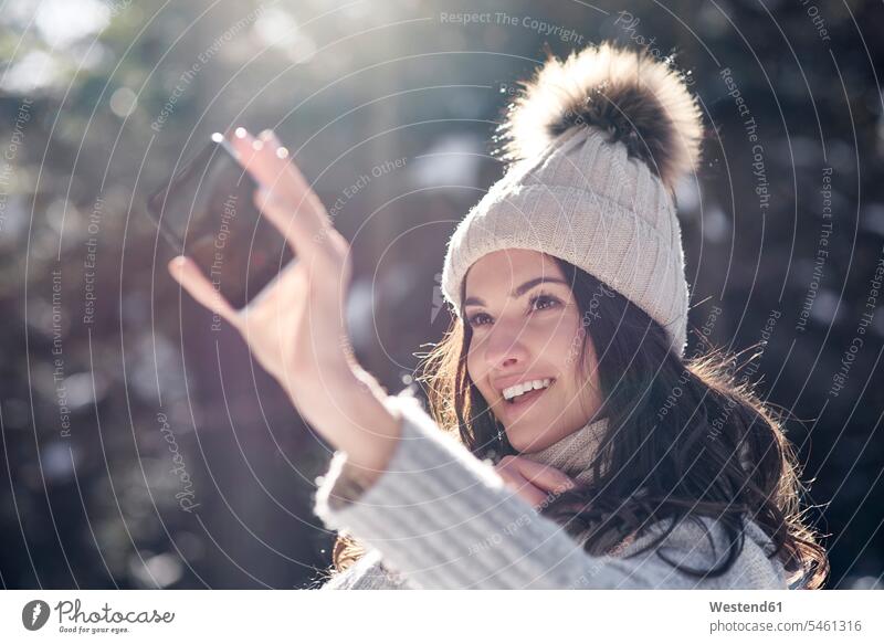 Portrait of smiling young woman taking selfie with smartphone in winter forest Selfie Selfies females women Smartphone iPhone Smartphones portrait portraits