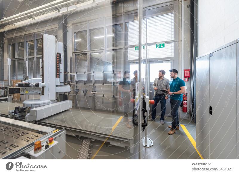 Two men looking at machine in modern factory man males eyeing factories contemporary Adults grown-ups grownups adult people persons human being humans