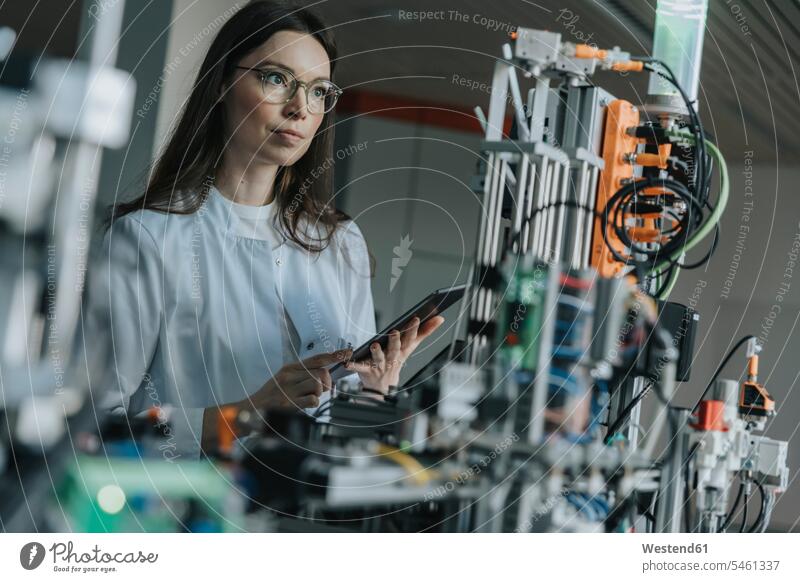 Female scientist holding digital tablet while examining machinery in laboratory color image colour image indoors indoor shot indoor shots interior interior view