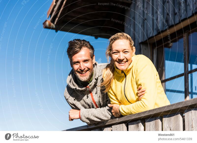 Couple leaning on balcony of a mountain hut, smiling mountaineering rested on couple twosomes partnership couples mountain pasture hiking hike mountain range