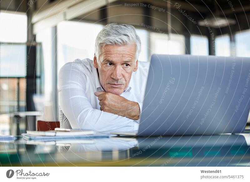 Businessman sitting at desk, trying to solve a problem Problem Problems difficulties Difficulty problematic using laptop using a laptop Using Laptops working