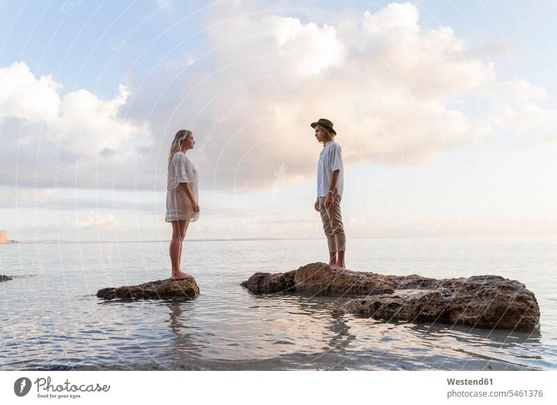 Young couple standing on rocks in front of the sea, Ibiza, Balearic Islands, Spain human human being human beings humans person persons caucasian appearance