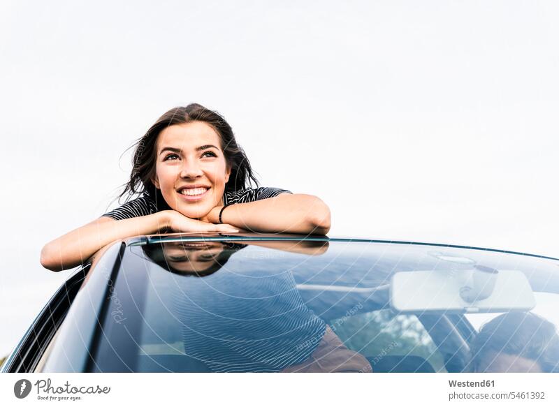 Smiling young woman looking out of sunroof of a car automobile Auto cars motorcars Automobiles females women view seeing viewing smiling smile motor vehicle