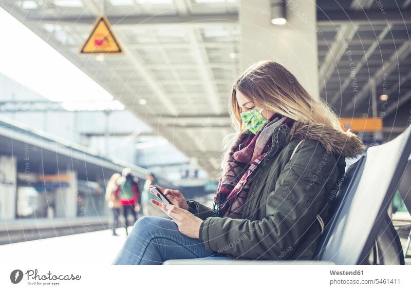 Young woman with smartphone wearing mask at station platform human human being human beings humans person persons caucasian appearance caucasian ethnicity