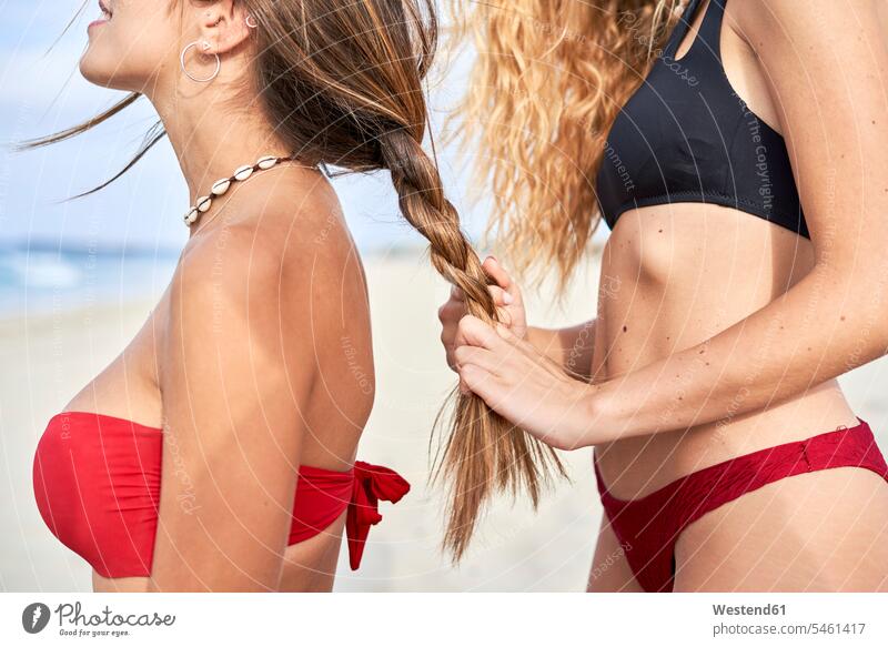 Young woman braidng the hair of her friend on the beach human human being human beings humans person persons caucasian appearance caucasian ethnicity european 2