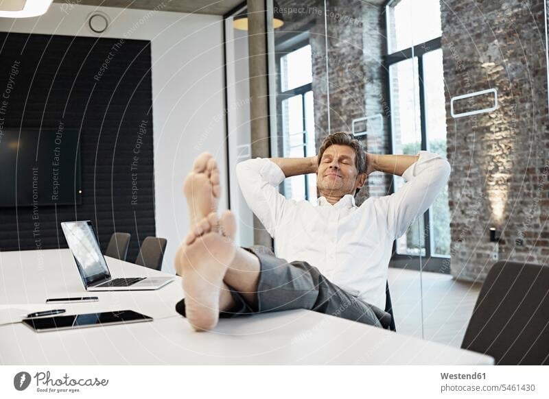 Barefooted businessman relaxing in conference room of modern office meeting room conference rooms meeting rooms offices office room office rooms Businessman