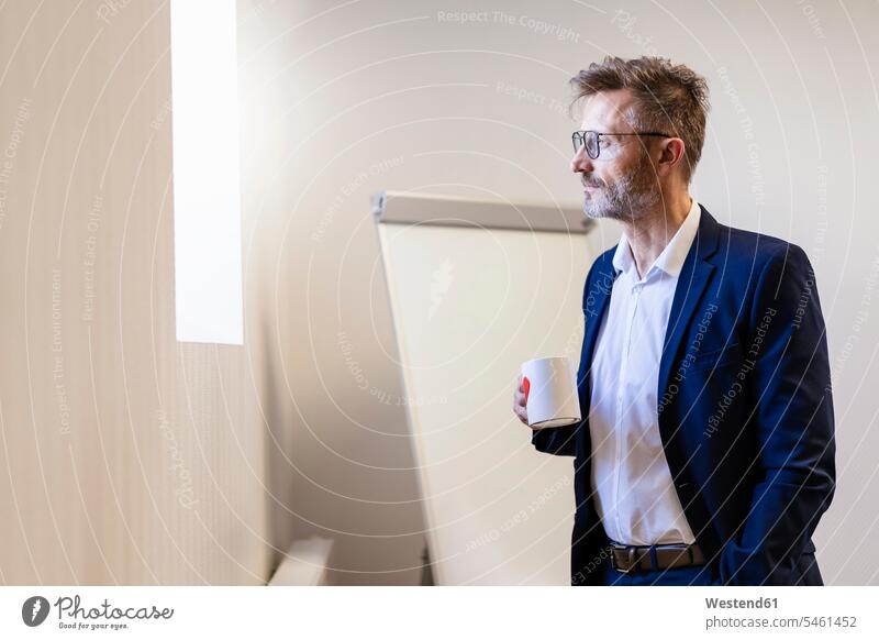 Businessman holding cup of coffee in office offices office room office rooms Business man Businessmen Business men Coffee Cup Coffee Cups workplace work place
