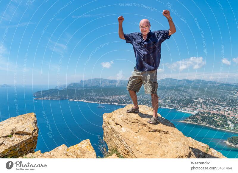 Senior man standing on cliff Freedom Liberty free men males cliffs Success successful raising arms arm up Hands Raised arm raised Hands Up arms up Hand Up