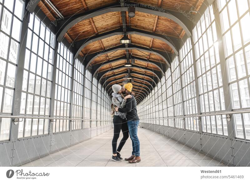 Young couple kissing at a subway station, Berlin, Germany touristic tourists windows glass panes kisses travel traveling embrace Embracement hug hugging seasons