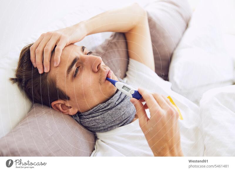 Close-up of sick man with thermometer in mouth resting on bed at home color image colour image Germany indoors indoor shot indoor shots interior interior view