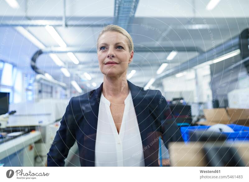 Confident blond businesswoman standing while looking away in illuminated factory color image colour image indoors indoor shot indoor shots interior