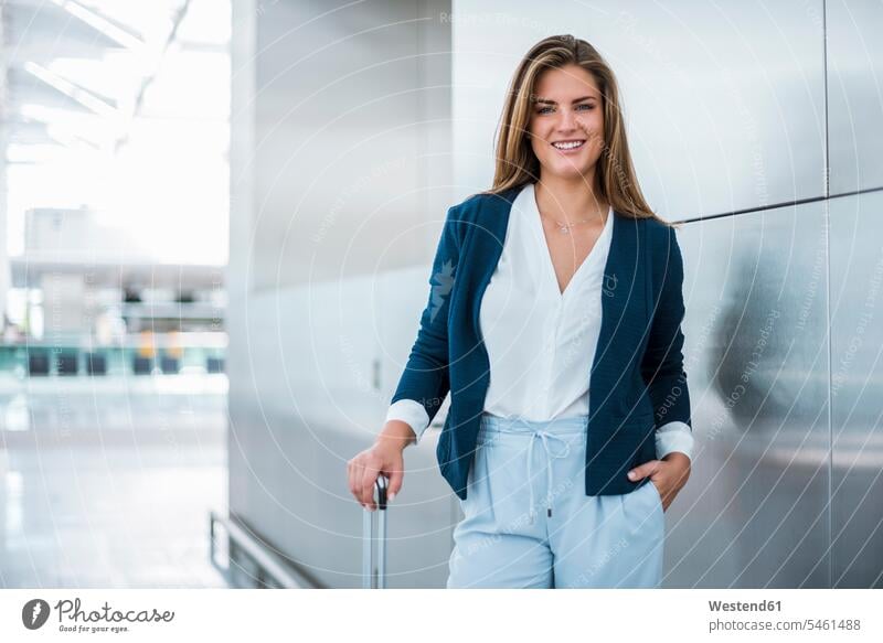 Portrait of smiling young businesswoman with luggage baggage smile portrait portraits businesswomen business woman business women females business people