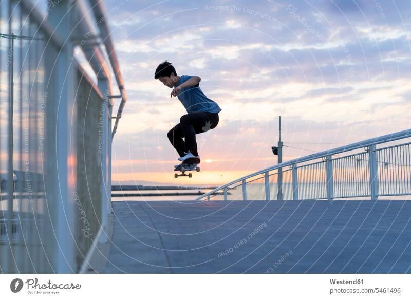 Young Chinese man skateboarding at sunsrise near the beach Chinese Ethnicity beaches young sunrise sun rise sunrises Boarding Skate Board skateboards jumping