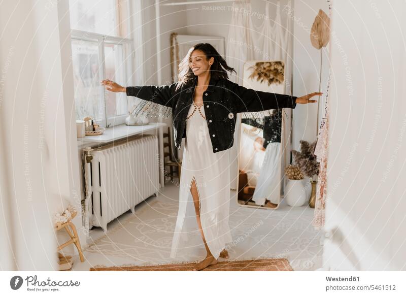 Bride dancing with arms outstretched wearing jacket while standing at wedding dress shop color image colour image indoors indoor shot indoor shots interior