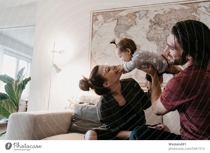 Happy family playing with baby girl in living room at home happiness happy families infants nurselings babies living rooms livingroom people persons human being