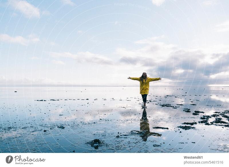 Woman with arms outstretched reflecting in sea at Hvalnes Nature Reserve Beach, Iceland color image colour image outdoors location shots outdoor shot