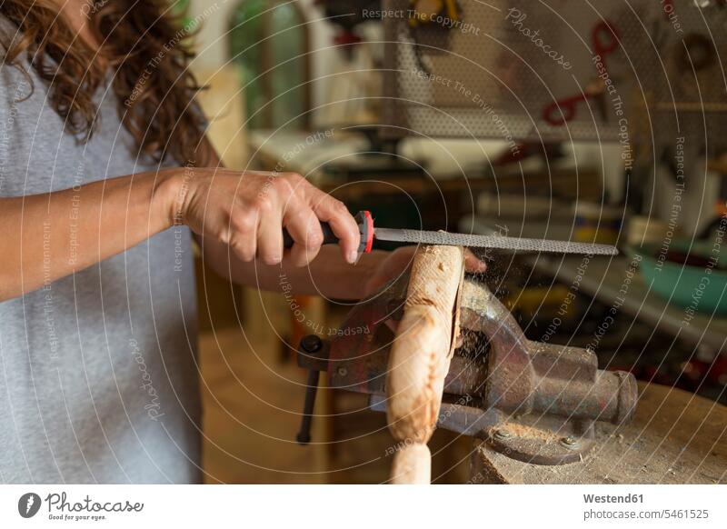 Craftswoman filing a piece of wood in her workshop craftswoman file females women handwork handcraft hand work manual labour manual work handicraft Adults