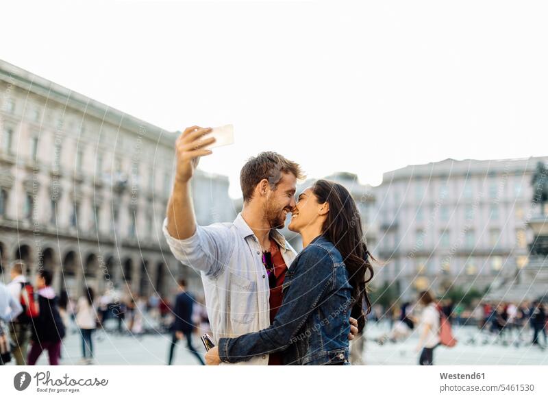 Happy young couple taking a selfie in the city, Milan, Italy touristic tourists telecommunication phones telephone telephones cell phone cell phones Cellphone