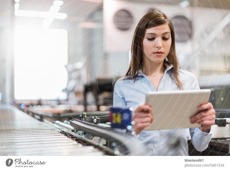 Female manager using digital tablet while standing by production line in factory color image colour image Austria indoors indoor shot indoor shots interior