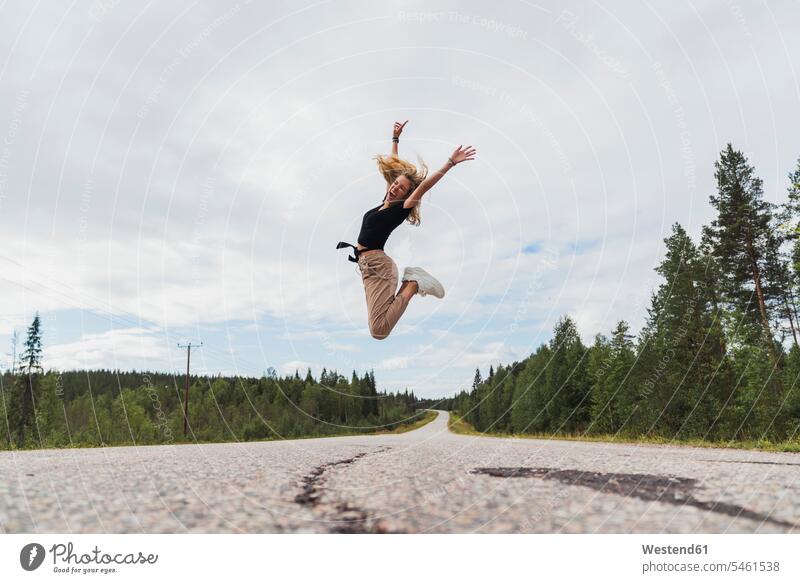 Finland, Lapland, exuberant young woman jumping in rural landscape landscapes scenery terrain females women Leaping exuberance hilarity Frolic Adults grown-ups