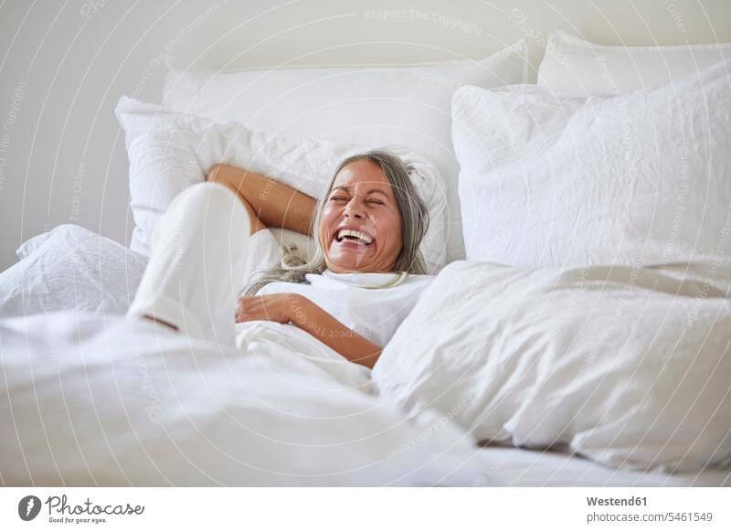 Cheerful woman lying on bed at home Germany indoors indoor shot indoor shots interior interior view Interiors day daylight shot daylight shots day shots daytime